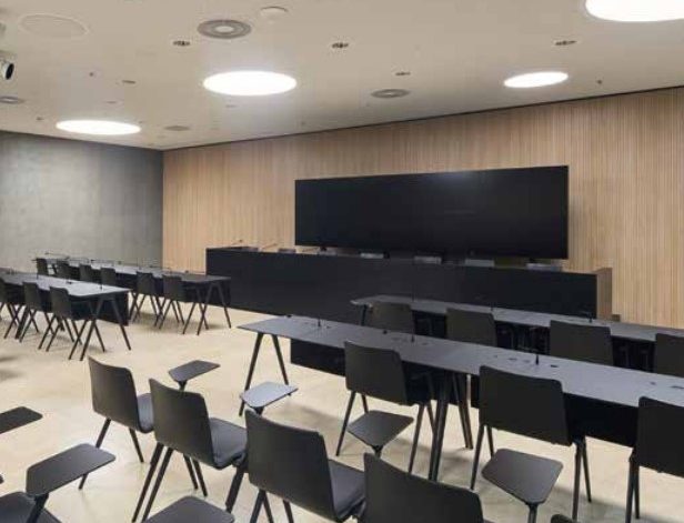 Brunner Reihenbestuhlung mit schwarzen Stühlen in modernem Konferenzraum Moderne Reihenbestuhlung mit schwarzen Stühlen und Tischen in einem großen Konferenzraum