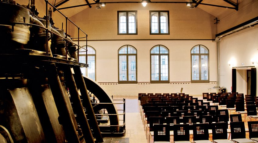 Saalbestuhlung als Reihenbestuhlung in historischer Industriehalle Reihenbestuhlung mit dunklen Stühlen in einer großen Industriehalle mit hohen Fenstern